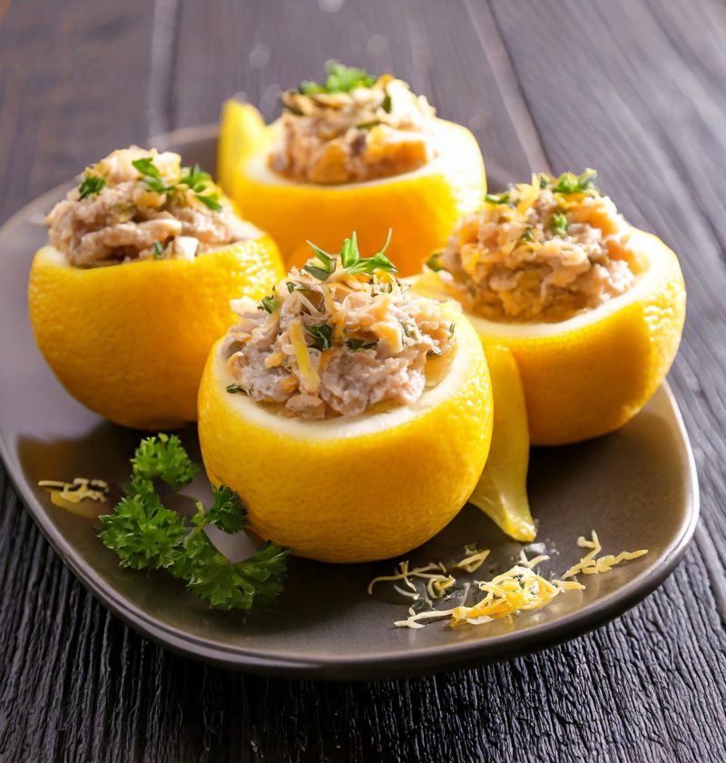 citron farcis à la mousse de thon avec quelques herbes, servis sur une assiette noire