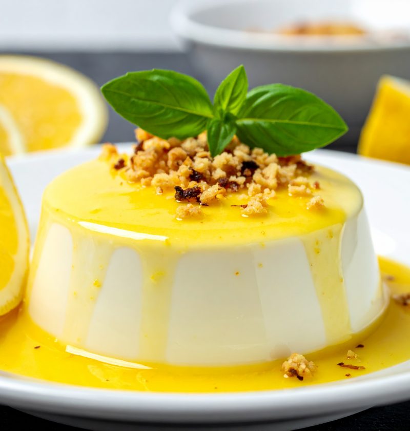 Panna cotta, sauce au citron et éclat de crumble. feuilles de basilic